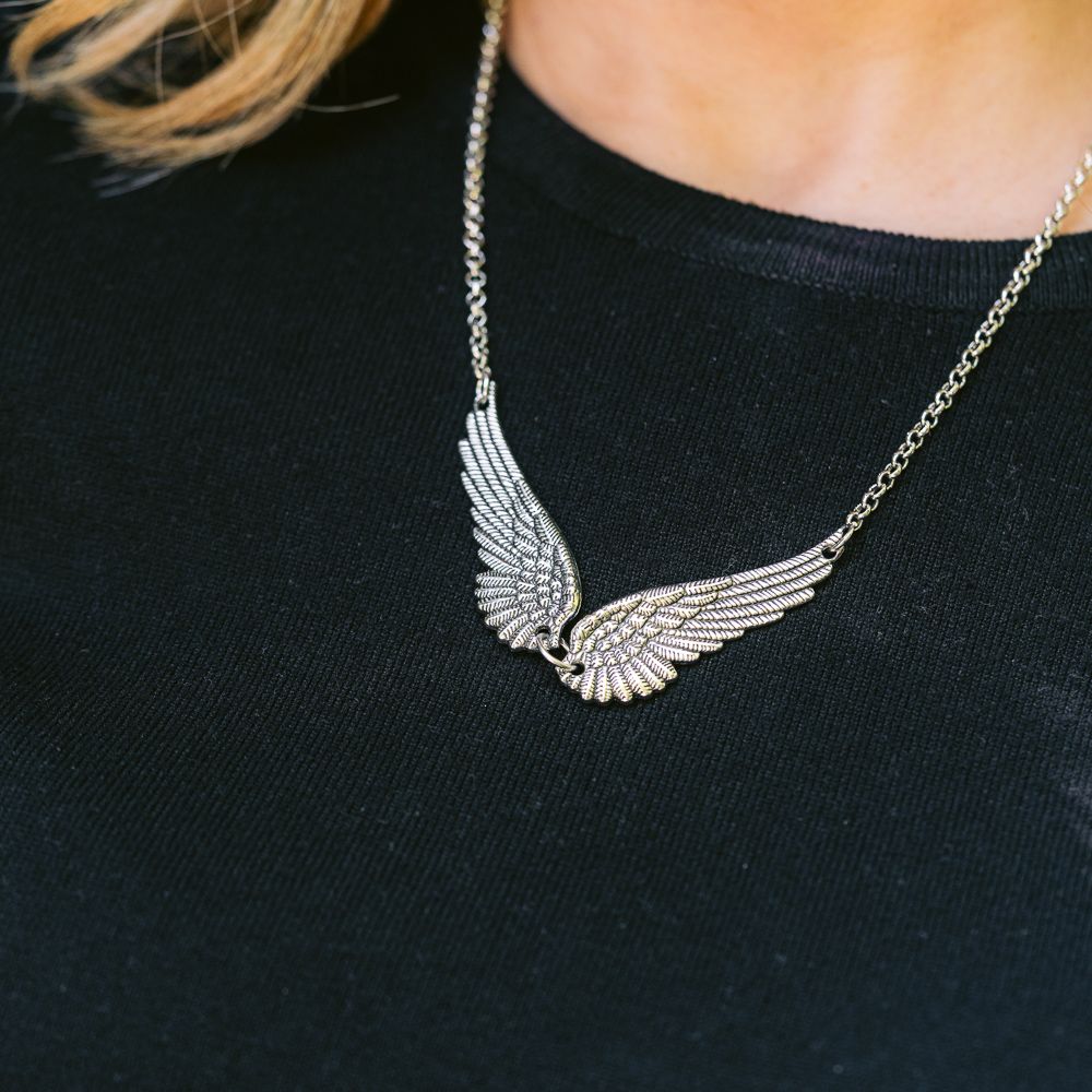 Collar plateado con alas sobre una blusa negra