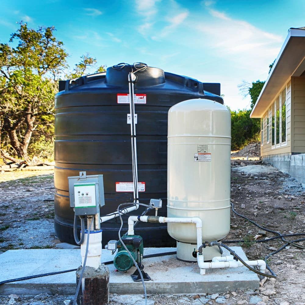 Black water tank and pressure tank system outdoors, next to a building.