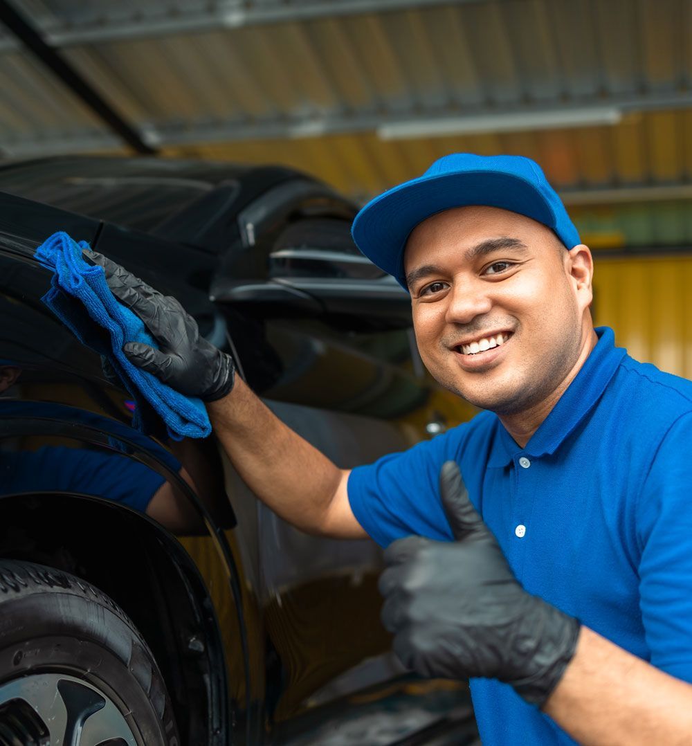 smiling car wash attendant while drying a car