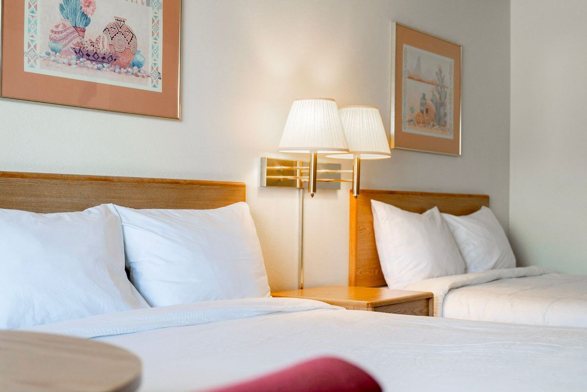 A hotel room with two beds and two lamps