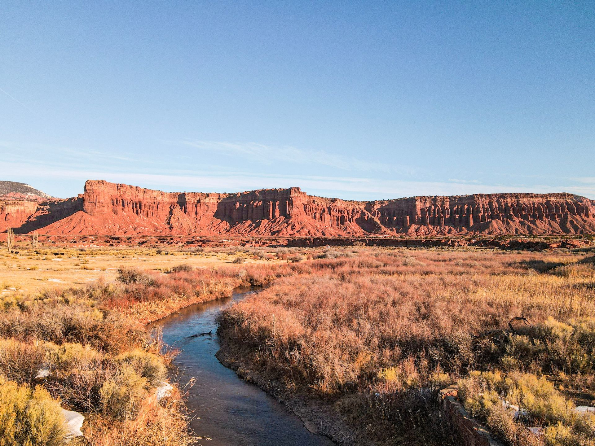 a creek running through a valley below red rocks