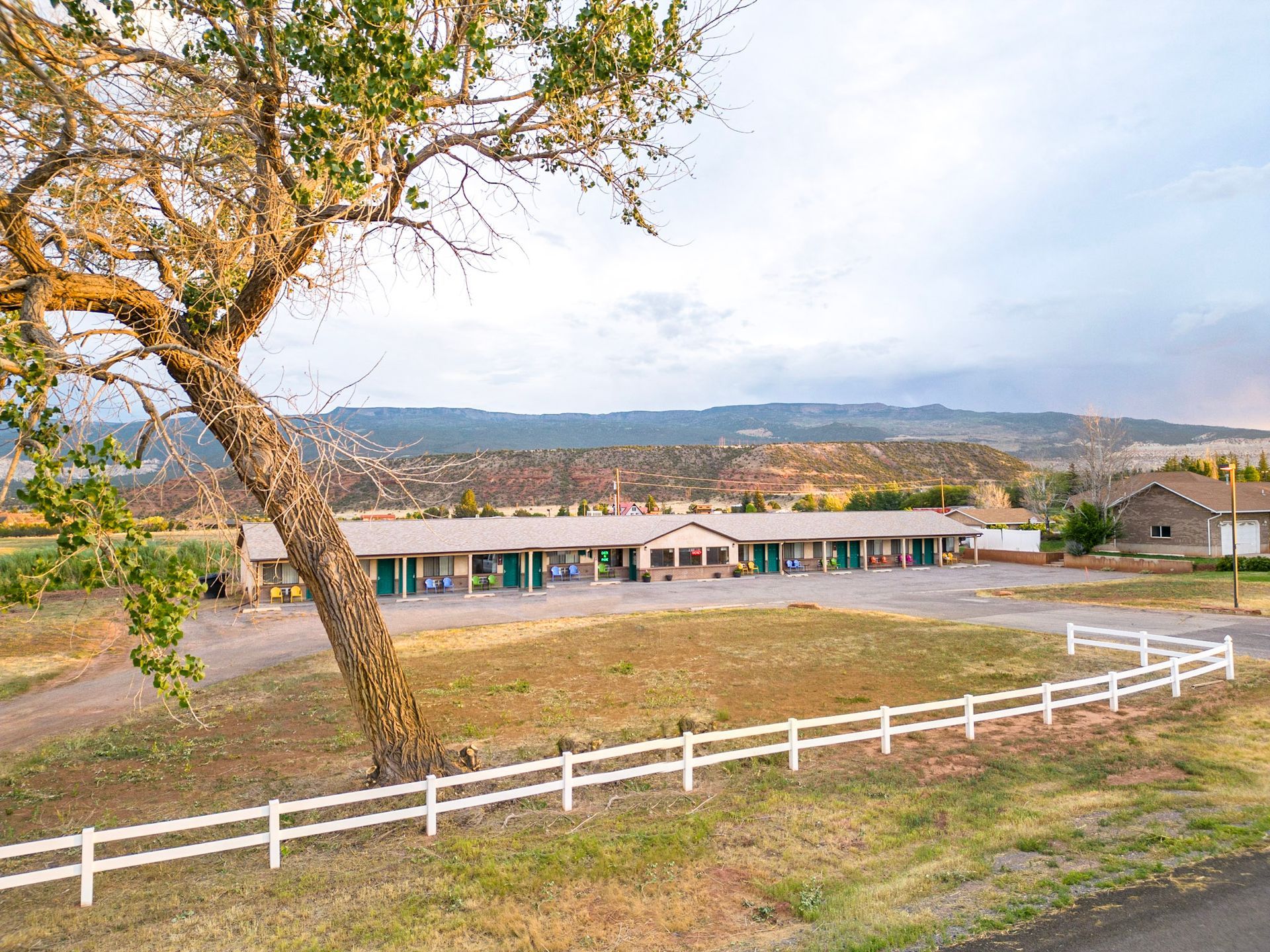 A motel with a white fence and a tree in front of it.