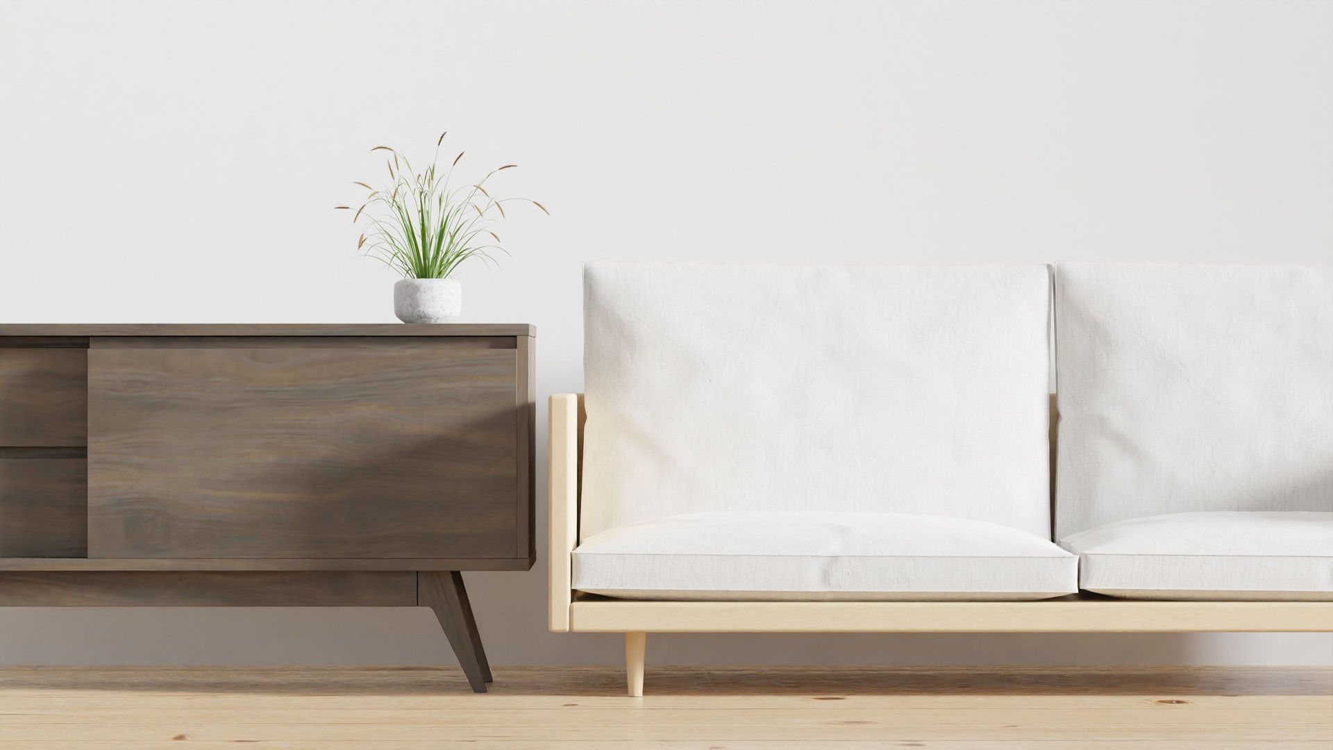 Minimalist living room with a wooden cabinet, potted plant, and white sofa on a light wall background