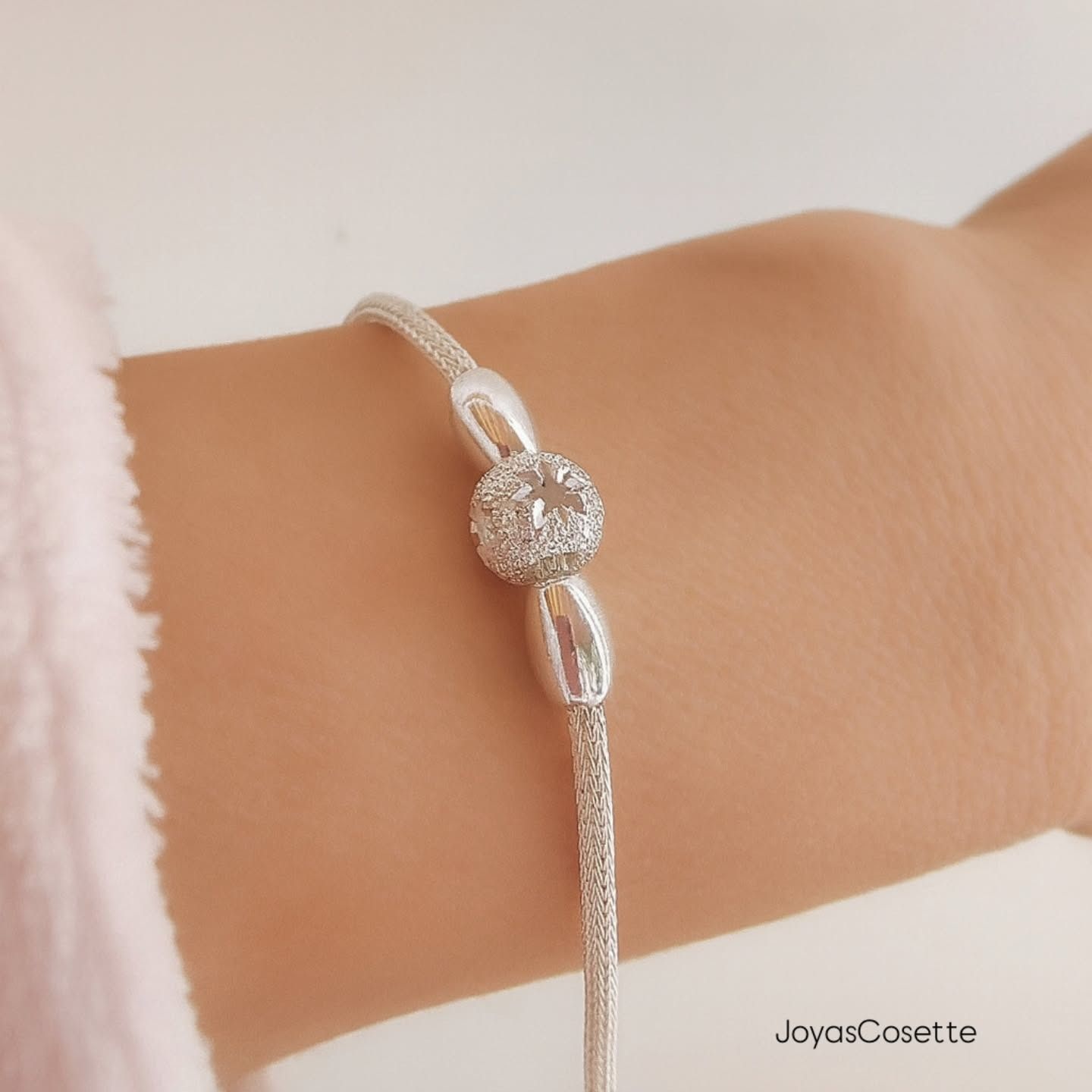 Pulsera de plata con charm circular central adornado con pequeñas piedras, para llevar en la muñeca.