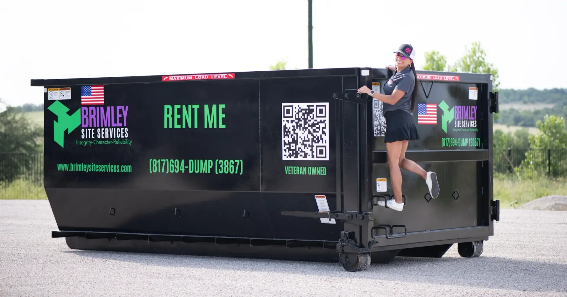 A man is standing next to a dumpster that says rent me on it.