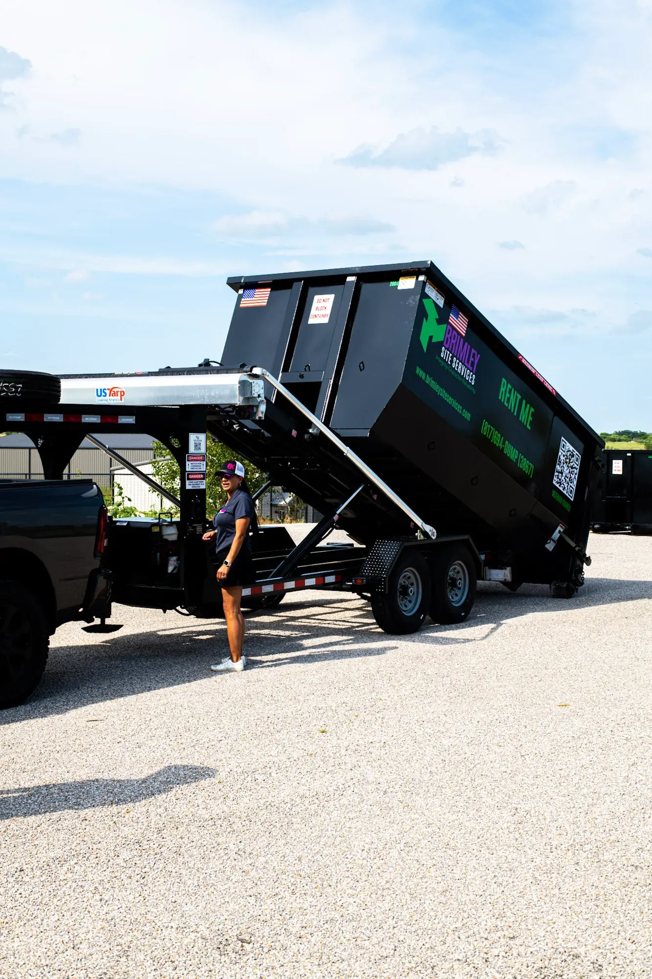 A man is standing next to a dumpster on a trailer.