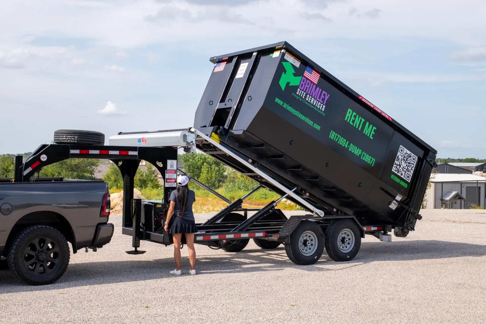A truck is pulling a dumpster on a trailer.