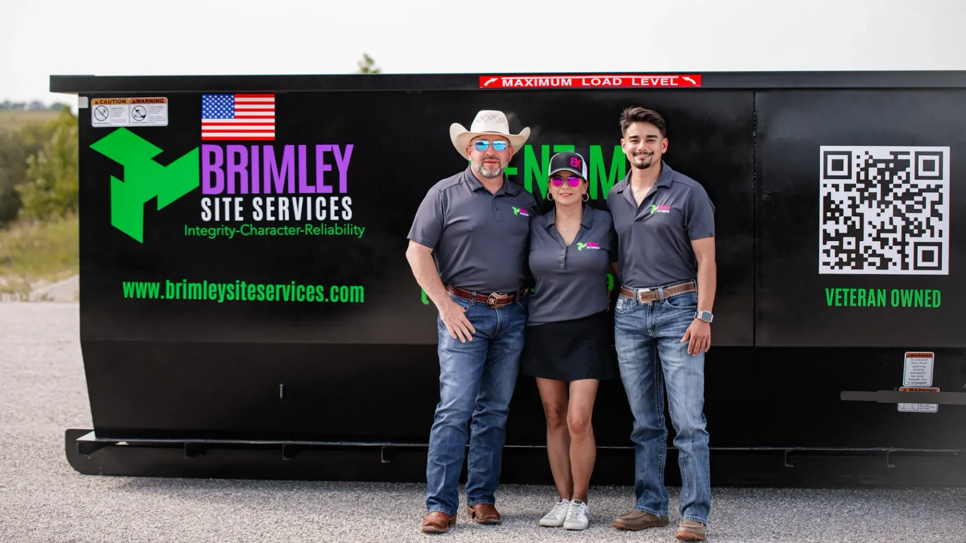 A group of people standing in front of a dumpster.