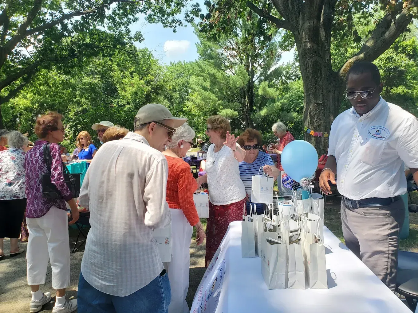 A group of people are standing around a table in a park.