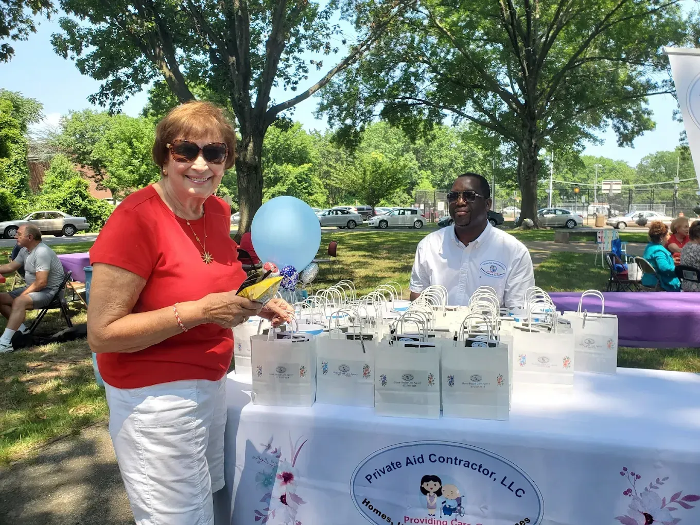 A woman is standing next to a table with balloons and bags on it.