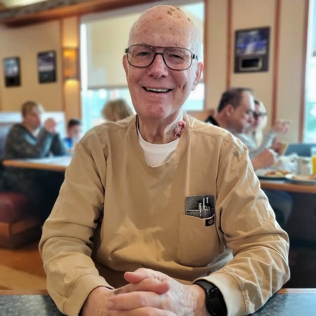 An older man wearing glasses is sitting at a table in a restaurant