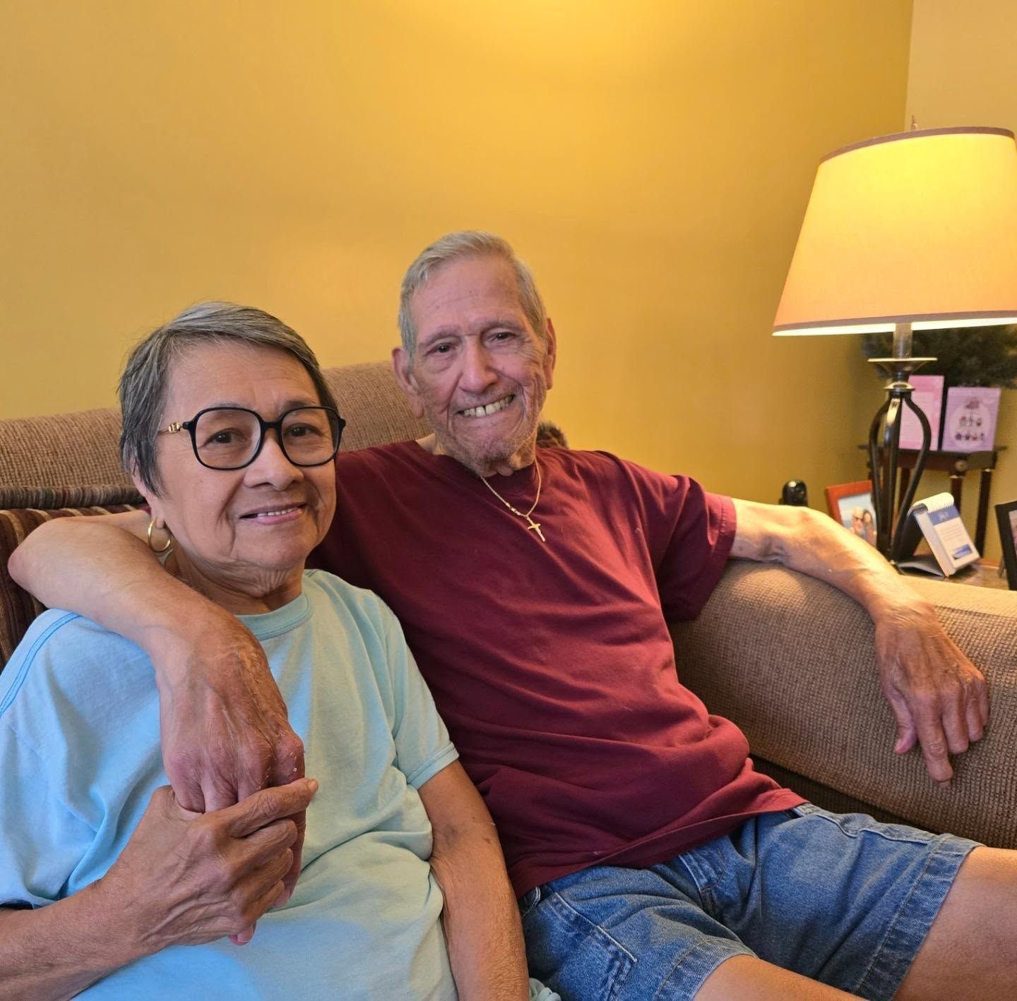 A man and woman are posing for a picture while sitting on a couch