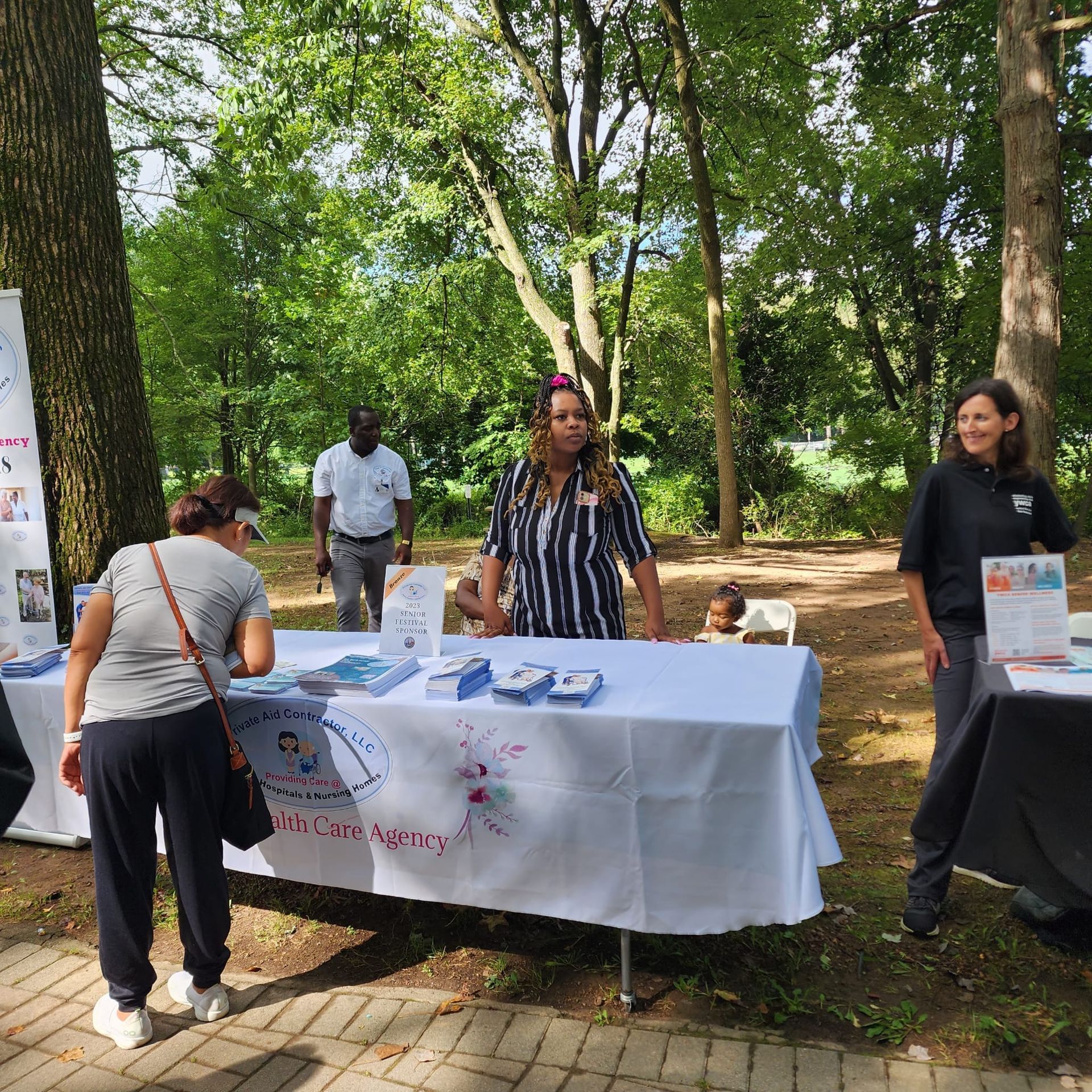 A group of people standing around a table in a park