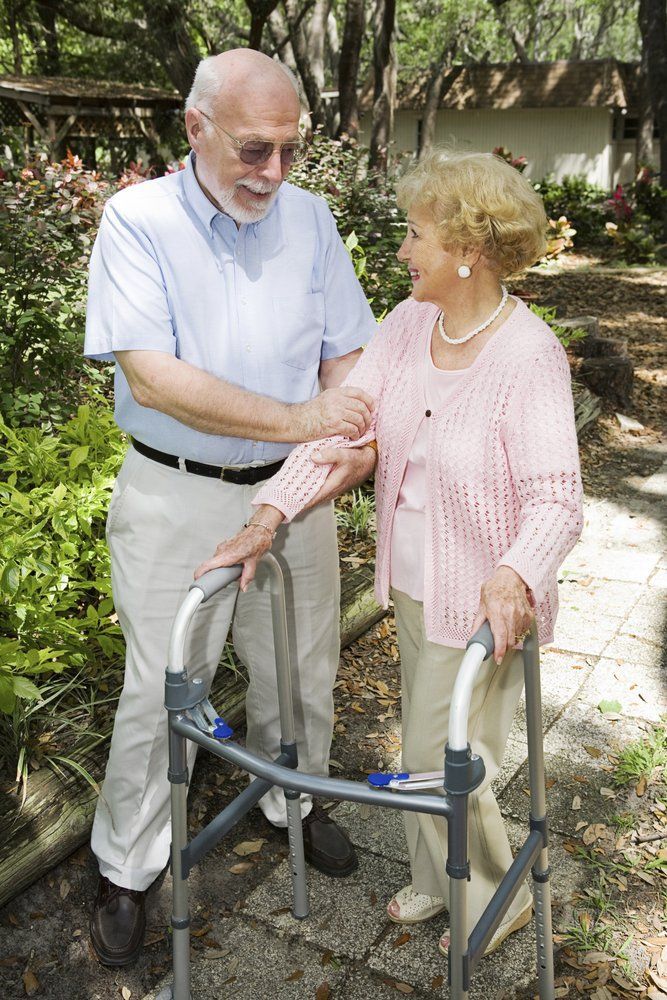 A man is helping an elderly woman with a walker.