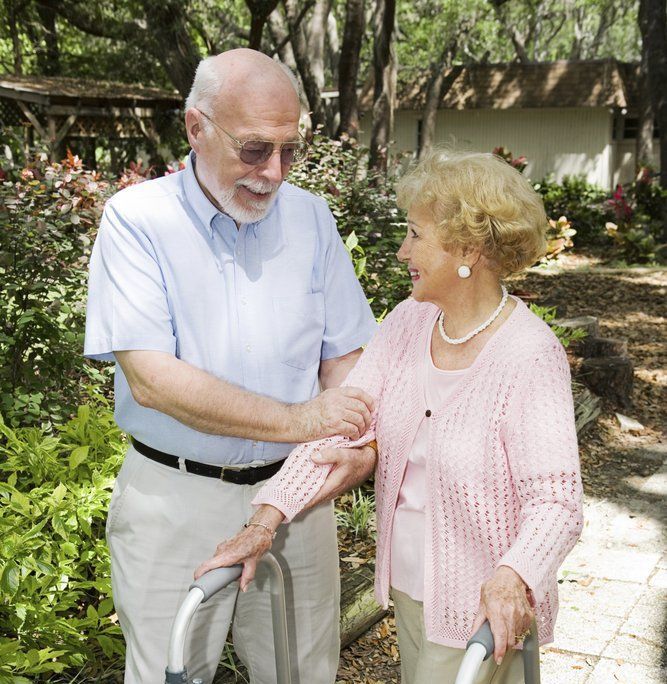 A man is helping an elderly woman with a walker