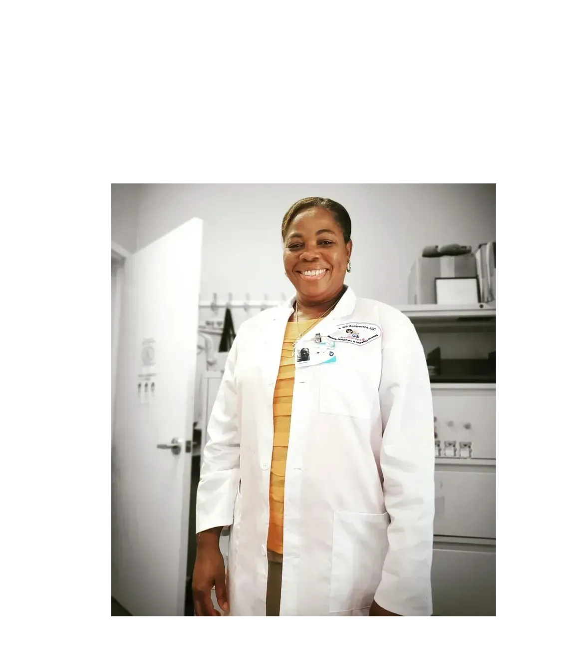 A woman in a lab coat is smiling in a room.