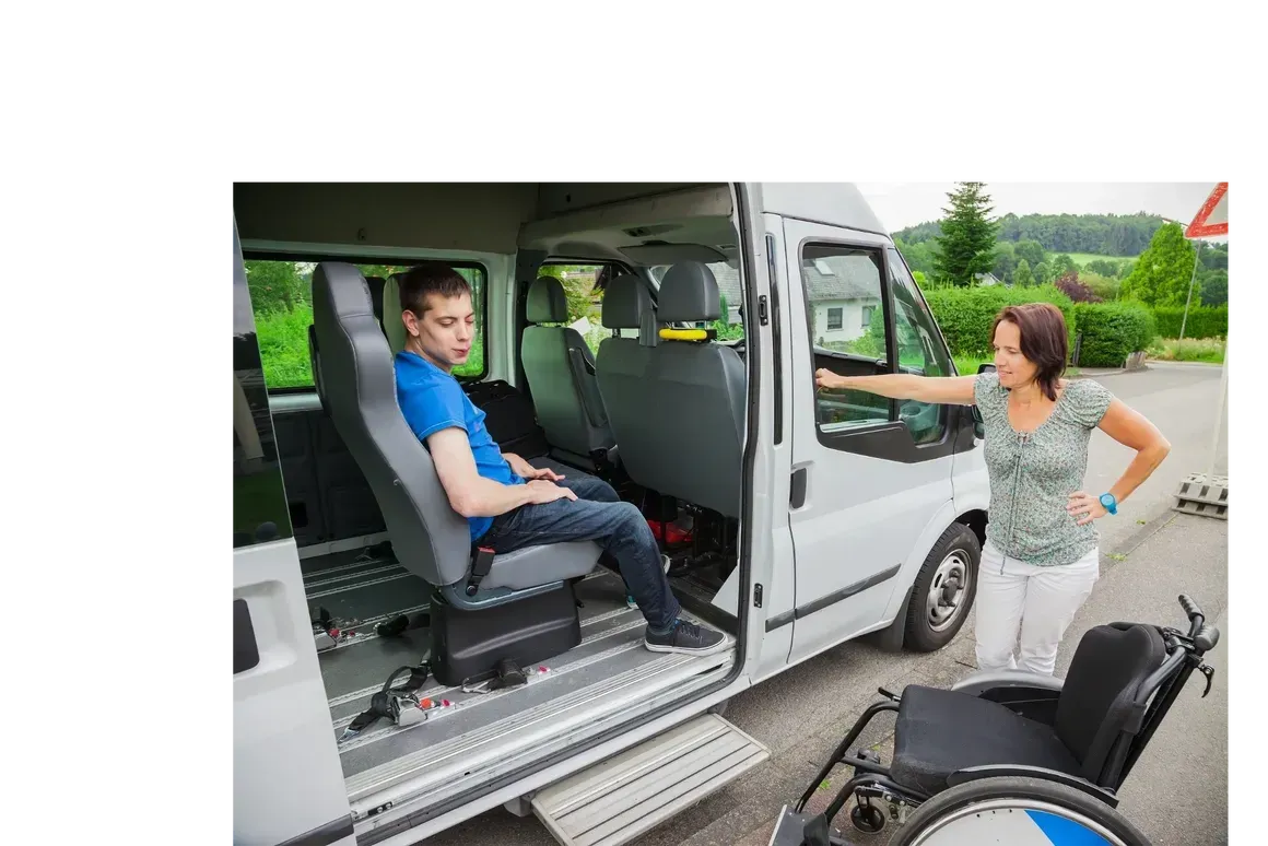 A woman is standing next to a van with a boy in the back seat.