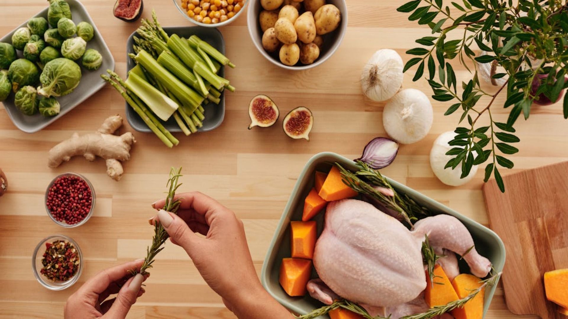 Una persona está preparando un pollo con verduras en una mesa de madera.