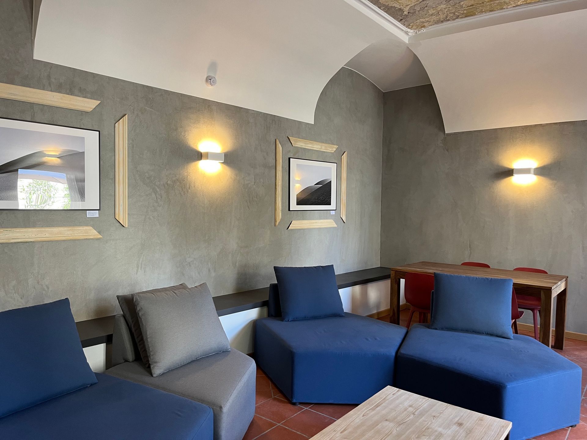 Un soggiorno moderno con pareti grigie, divani blu, opere d'arte e un tavolo da pranzo in legno.