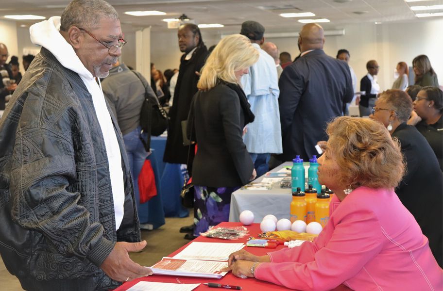 A woman working at a nonprofit event table talks with a man