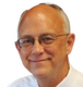 A man wearing glasses and a white shirt smiles for the camera