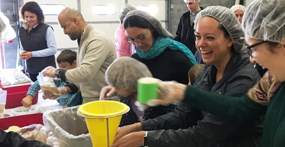 A group of volunteers packages food in an assembly line