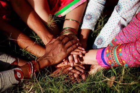 A group of people are putting their hands together in the grass.