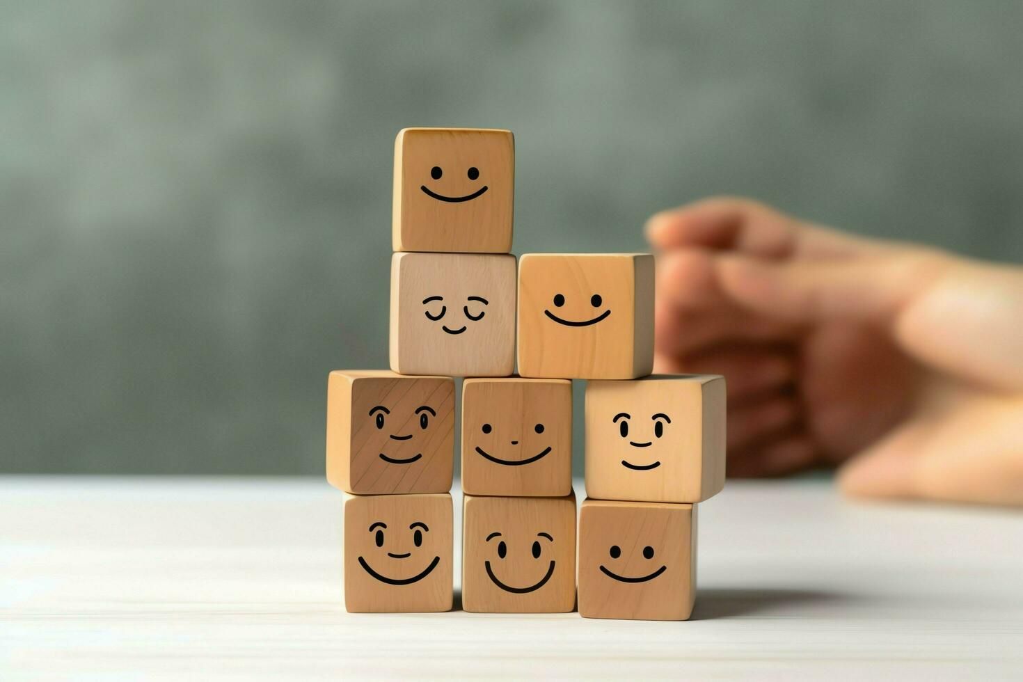 A person is stacking wooden blocks with smiley faces on them.