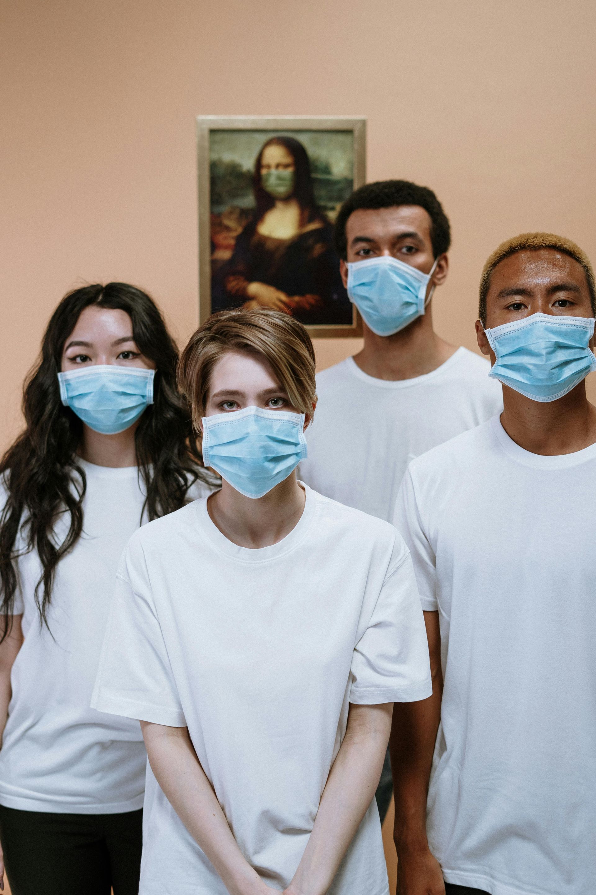 Four healthcare professionals wearing masks in front of a painting of the Mona Lisa, also masked. Museum setting.