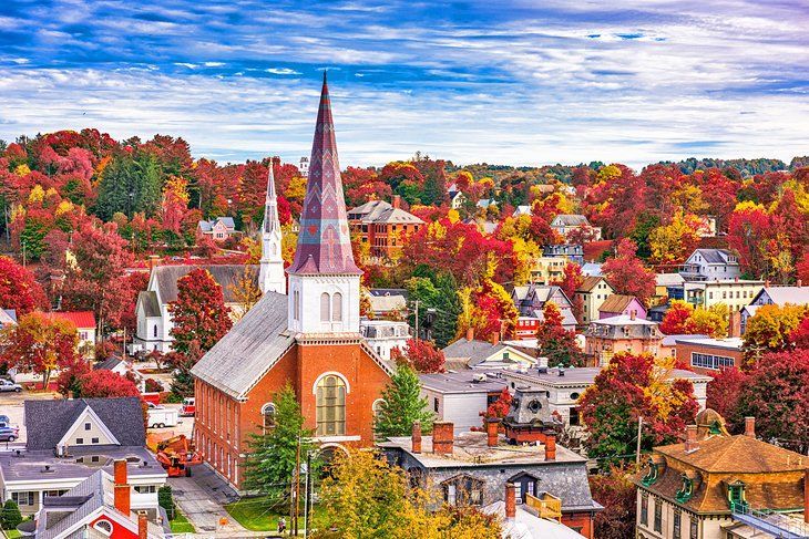 Autumnal townscape, red brick church with tall spire, surrounded by trees in fall colors.
