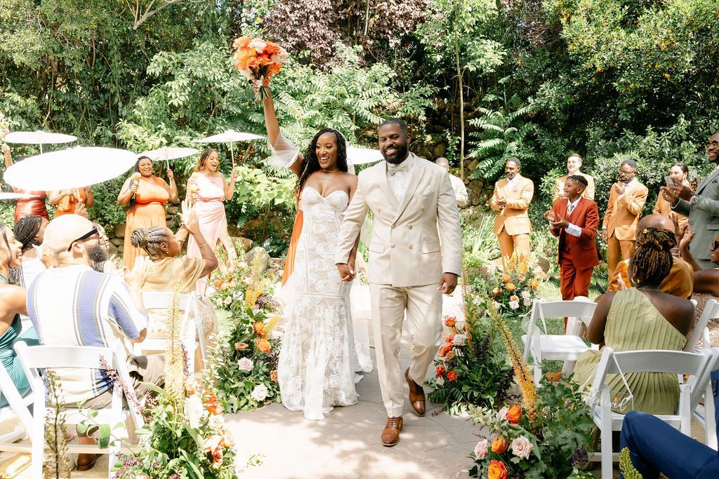 A bride and groom are walking down the aisle at their wedding holding hands.