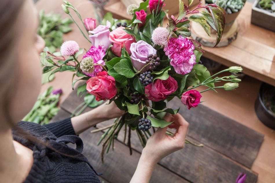 A woman is holding a bouquet of flowers on a wooden table.