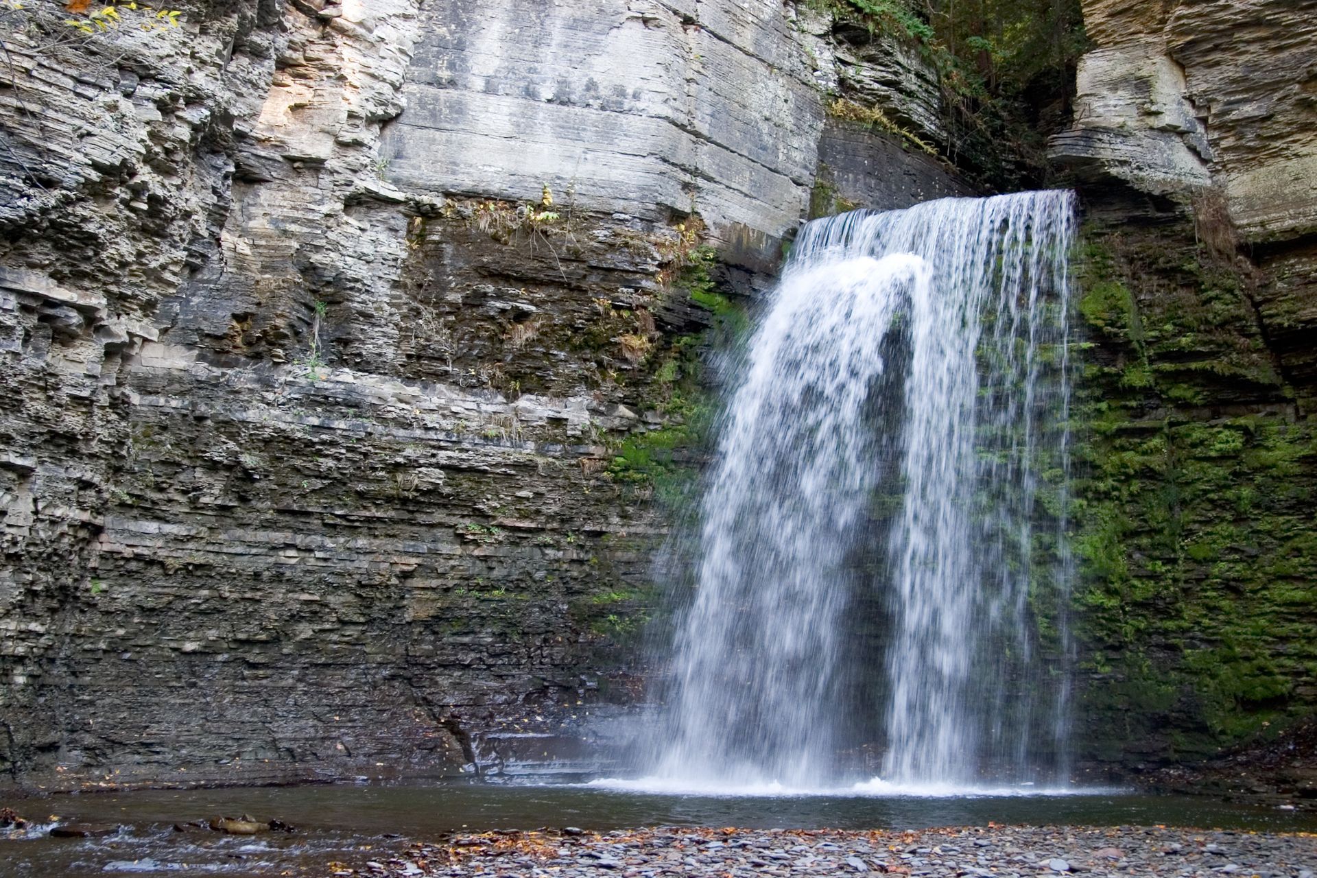 A waterfall is surrounded by rocks and trees in the middle of a forest.