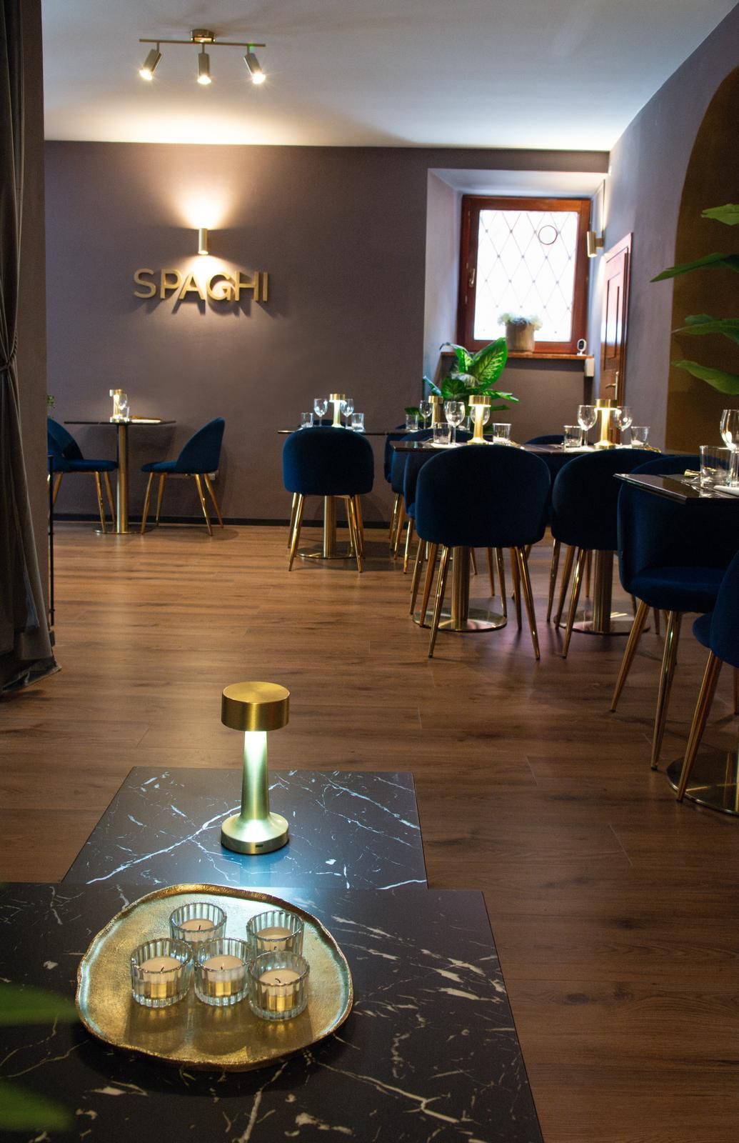 Un ristorante con tavoli e sedie e un vassoio di candele su un tavolo.