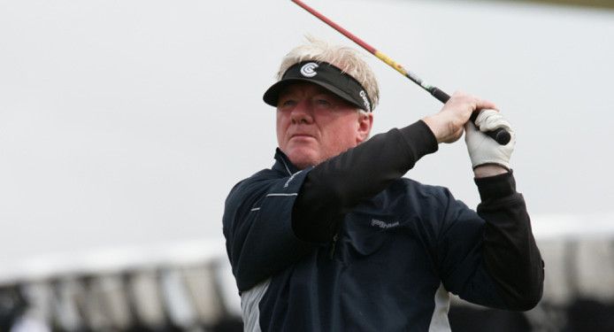 A man wearing a visor is swinging a golf club