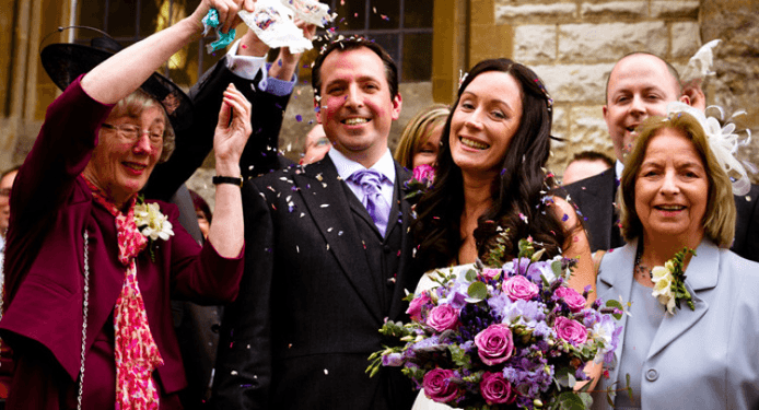 A bride and groom are posing for a picture with their wedding guests.