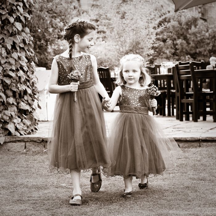 A black and white photo of two flower girls walking down the aisle