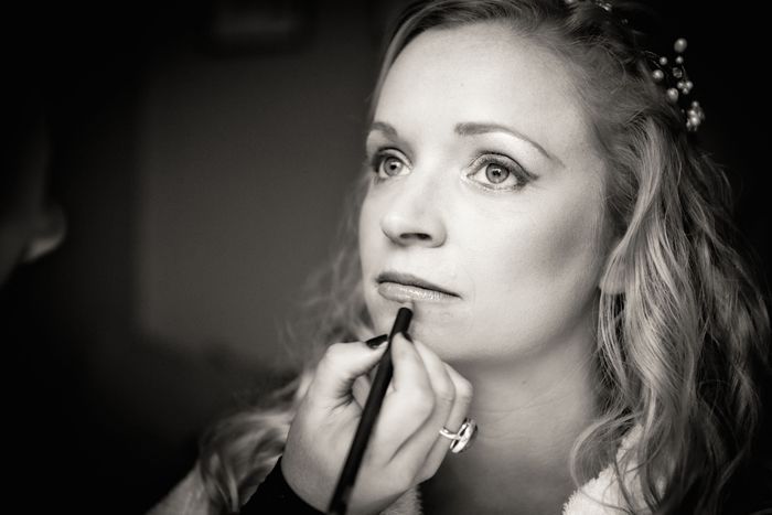 A woman is getting her makeup done in a black and white photo.