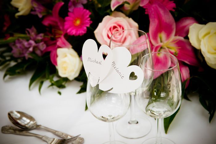 A couple of wine glasses sitting on a table with flowers in the background