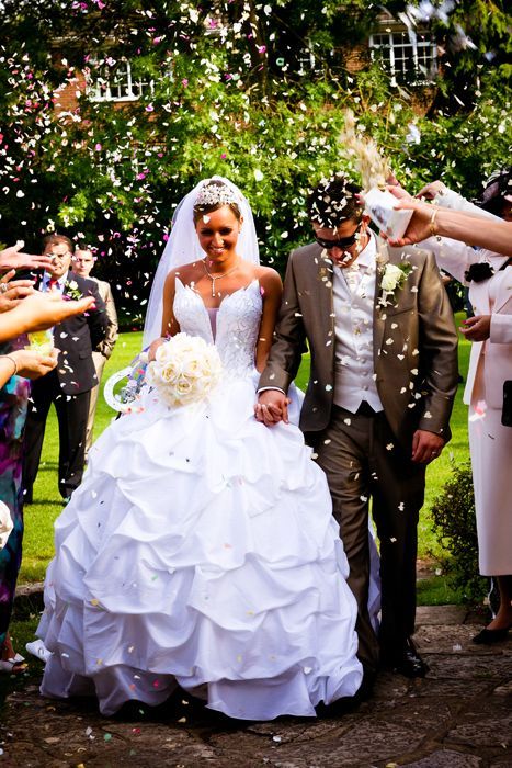 A bride and groom are being showered with confetti at their wedding