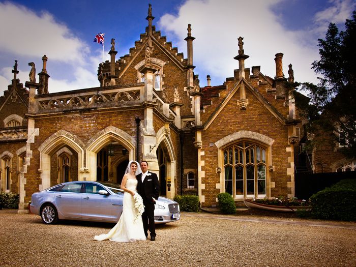 A bride and groom pose in front of a castle