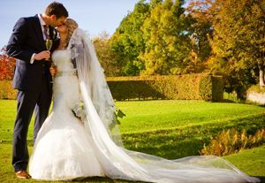 A bride and groom are kissing in a park on their wedding day.