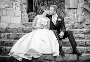 A bride and groom are kissing while sitting on a set of stairs.