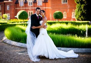 A bride and groom are posing for a picture in front of a brick building.