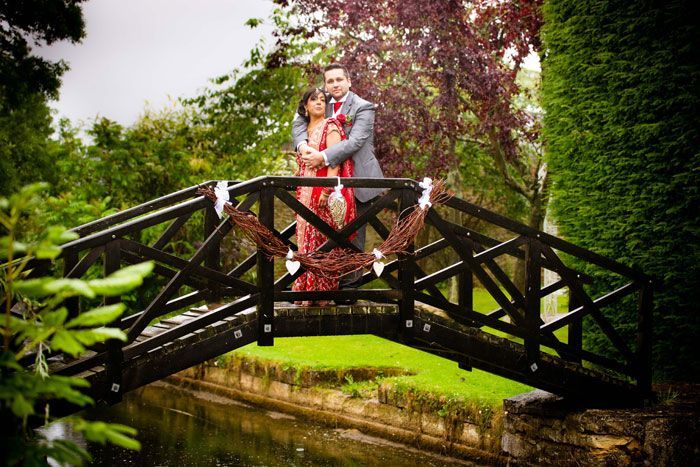 A man and a woman are standing on a bridge over a river.