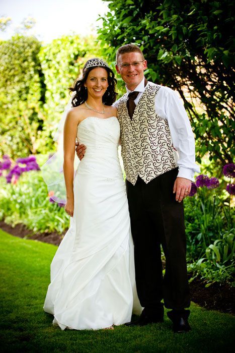 A bride and groom are posing for a picture in a garden.