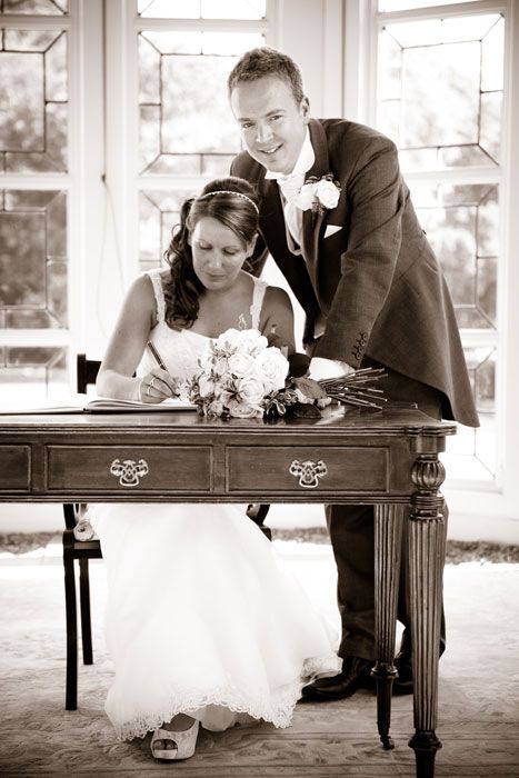 A bride and groom are signing a wedding register at a table.