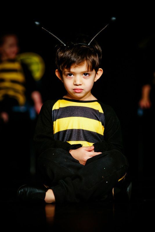 A young boy in a bee costume is sitting on a chair.