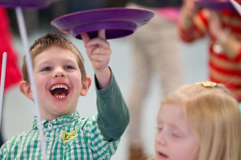 A young boy is holding a purple plate up in the air.