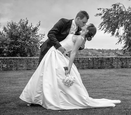 A bride and groom kissing in a black and white photo
